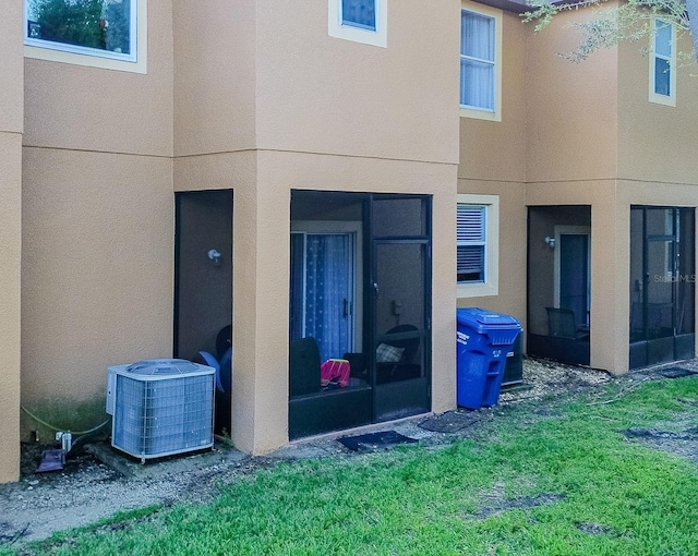 exterior space with central AC unit and a lawn