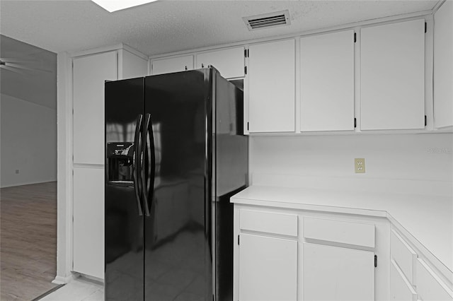 kitchen with white cabinetry, black refrigerator with ice dispenser, light hardwood / wood-style flooring, and a textured ceiling