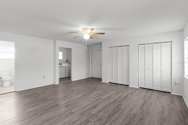 unfurnished bedroom featuring connected bathroom, light wood-type flooring, ceiling fan, two closets, and independent washer and dryer