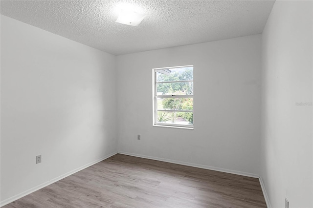 unfurnished room with a textured ceiling and light hardwood / wood-style floors