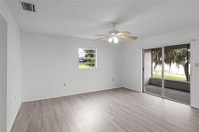 unfurnished room with ceiling fan, a textured ceiling, and light wood-type flooring