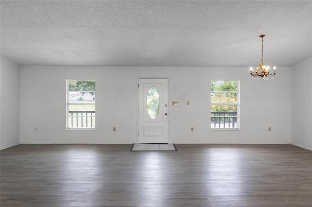 foyer entrance with dark wood-type flooring, a chandelier, and a textured ceiling