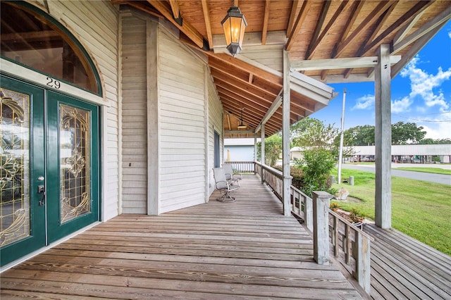 wooden terrace with french doors, a porch, and a lawn