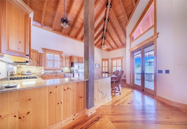 kitchen with light wood-type flooring, beamed ceiling, appliances with stainless steel finishes, and light brown cabinetry