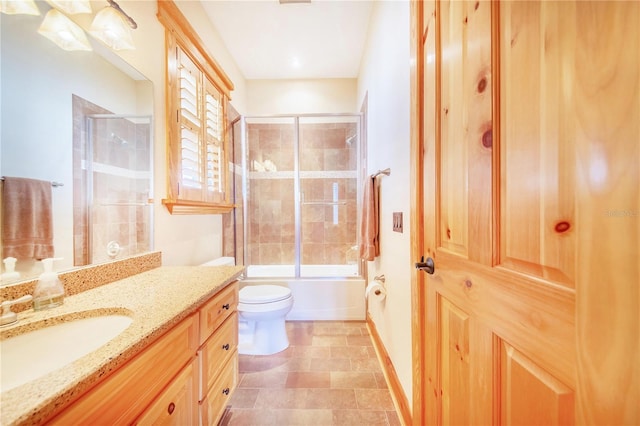 full bathroom with combined bath / shower with glass door, vanity, and toilet