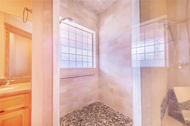 bathroom with tiled shower and vanity