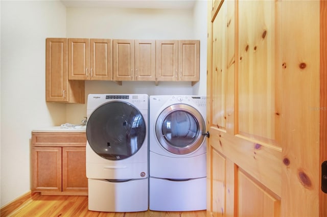 laundry area featuring cabinets, light wood-type flooring, and washing machine and clothes dryer