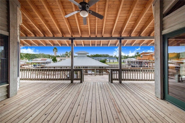 wooden terrace with a water view, ceiling fan, and a gazebo