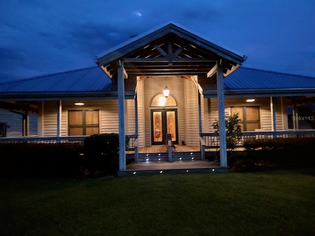 back house at night featuring a yard and covered porch