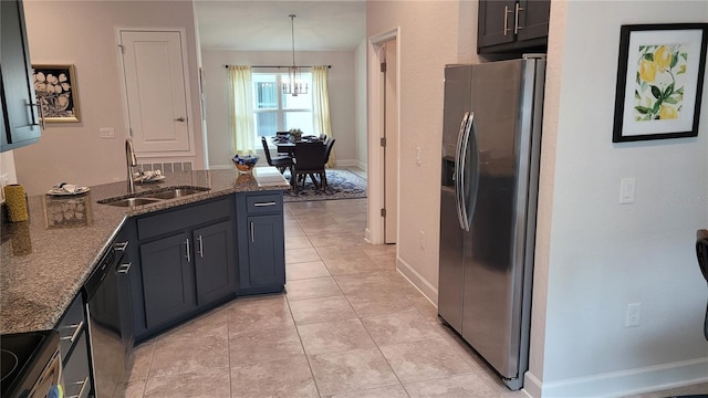 kitchen with appliances with stainless steel finishes, sink, an inviting chandelier, dark stone countertops, and hanging light fixtures