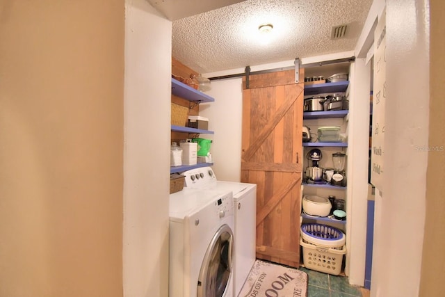 laundry area featuring washer and dryer, a textured ceiling, and a barn door