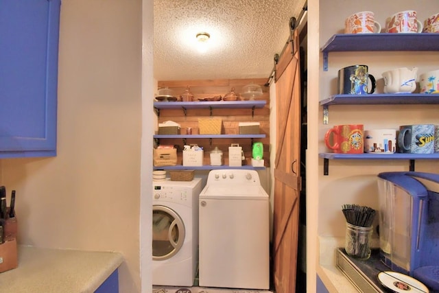 laundry area with a barn door, separate washer and dryer, and a textured ceiling