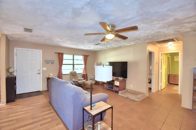 living room with ceiling fan and a textured ceiling