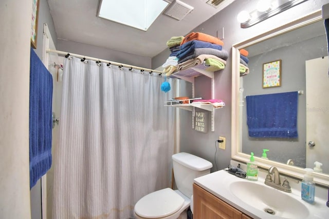 bathroom featuring vanity, toilet, a skylight, and walk in shower