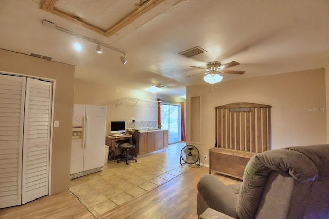 interior space featuring rail lighting, ceiling fan, and light hardwood / wood-style flooring