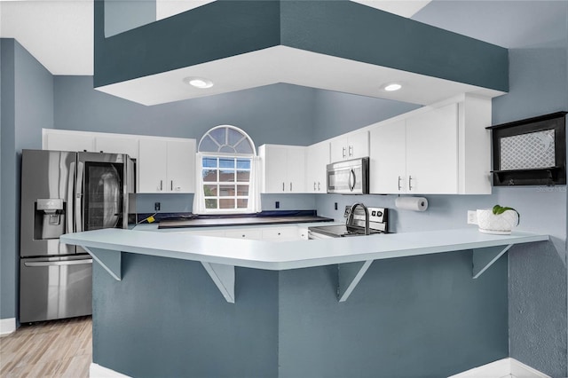 kitchen with stainless steel appliances, white cabinetry, kitchen peninsula, and a breakfast bar area