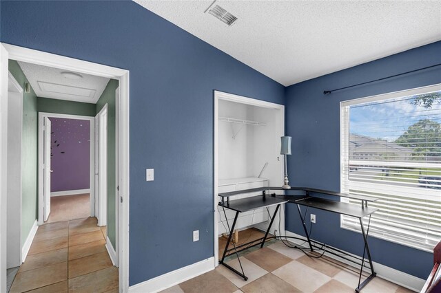 office space with vaulted ceiling, a textured ceiling, and light tile patterned floors