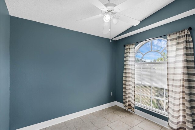 tiled empty room with a wealth of natural light, vaulted ceiling, ceiling fan, and a textured ceiling