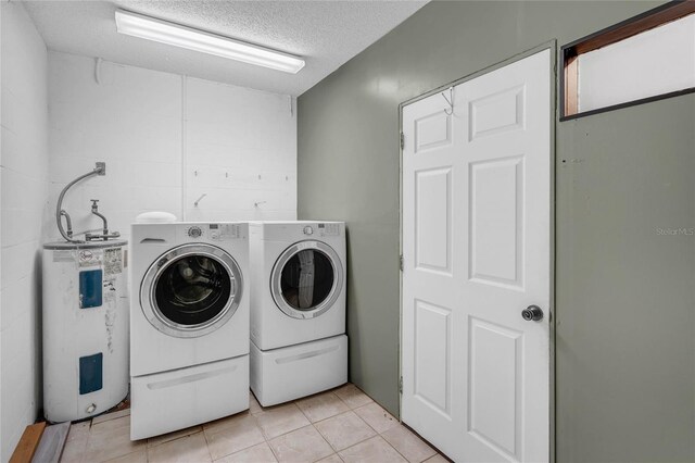 laundry room with a textured ceiling, light tile patterned floors, independent washer and dryer, and electric water heater