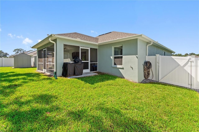 back of property with a lawn, a storage shed, and a sunroom