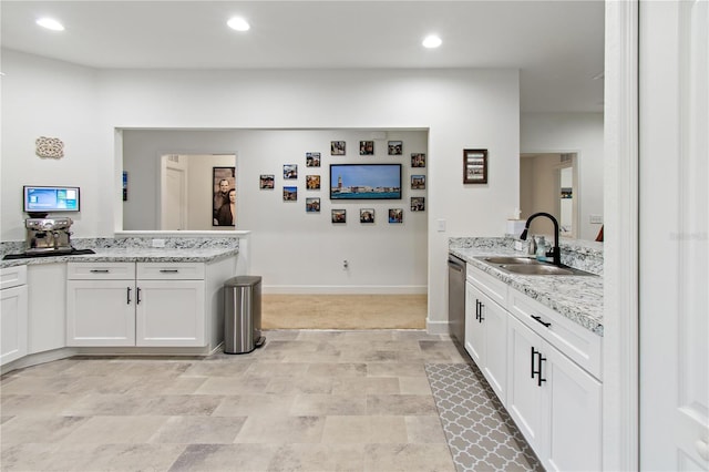 kitchen featuring dishwasher, sink, kitchen peninsula, light stone counters, and white cabinetry