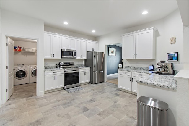 kitchen featuring light stone countertops, white cabinetry, washer and dryer, and appliances with stainless steel finishes