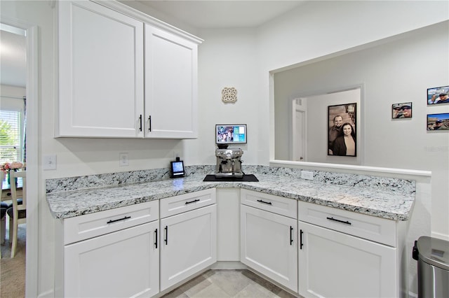 kitchen featuring light stone counters and white cabinetry