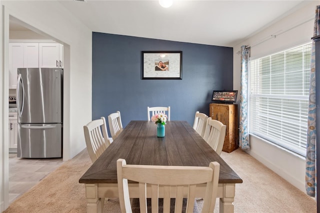 dining area featuring light carpet and vaulted ceiling