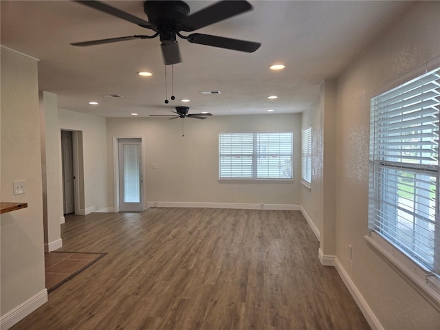 empty room with hardwood / wood-style floors, ceiling fan, and a healthy amount of sunlight