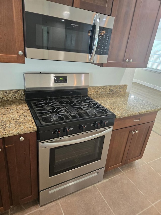 kitchen featuring light stone countertops, appliances with stainless steel finishes, and light tile patterned flooring