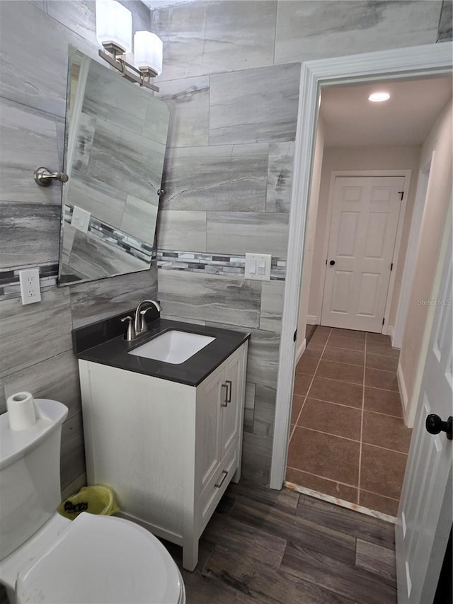 bathroom with tile walls, vanity, toilet, and hardwood / wood-style flooring