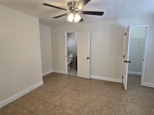 unfurnished bedroom with light tile patterned floors, a closet, ceiling fan, a walk in closet, and ensuite bath