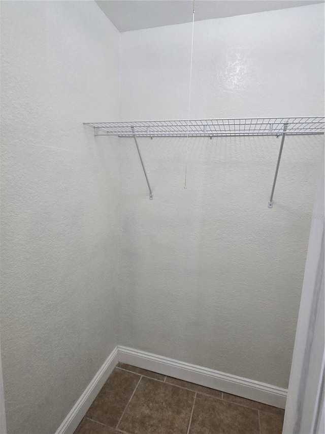 walk in closet featuring dark tile patterned floors