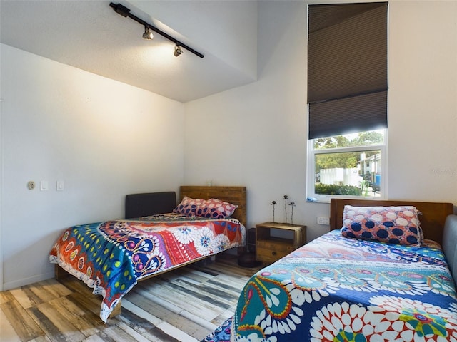 bedroom with track lighting and hardwood / wood-style flooring