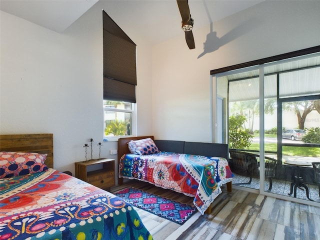 bedroom with access to outside, lofted ceiling, and wood-type flooring