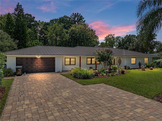 single story home featuring a lawn and a garage