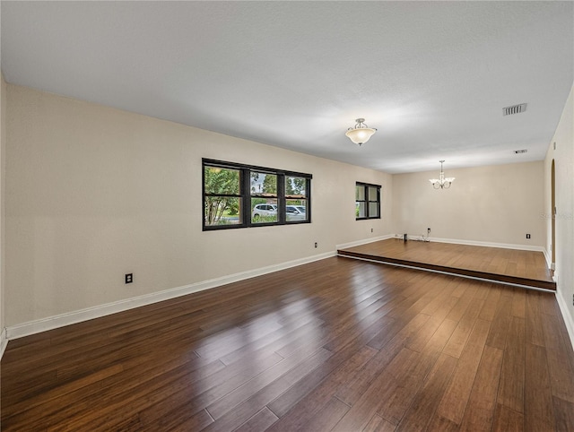 unfurnished room featuring a notable chandelier and dark hardwood / wood-style floors