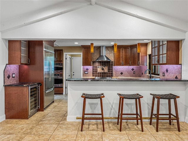 kitchen featuring wine cooler, kitchen peninsula, wall chimney exhaust hood, stainless steel appliances, and decorative backsplash