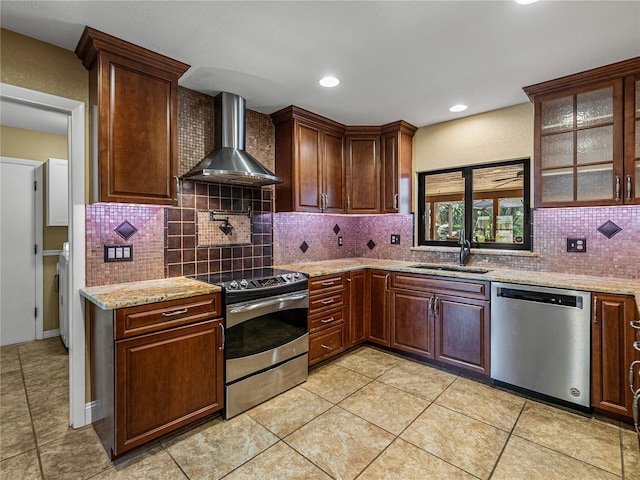 kitchen featuring decorative backsplash, appliances with stainless steel finishes, wall chimney range hood, and sink