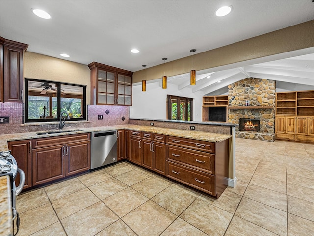 kitchen with ceiling fan, sink, stainless steel dishwasher, a stone fireplace, and lofted ceiling with beams