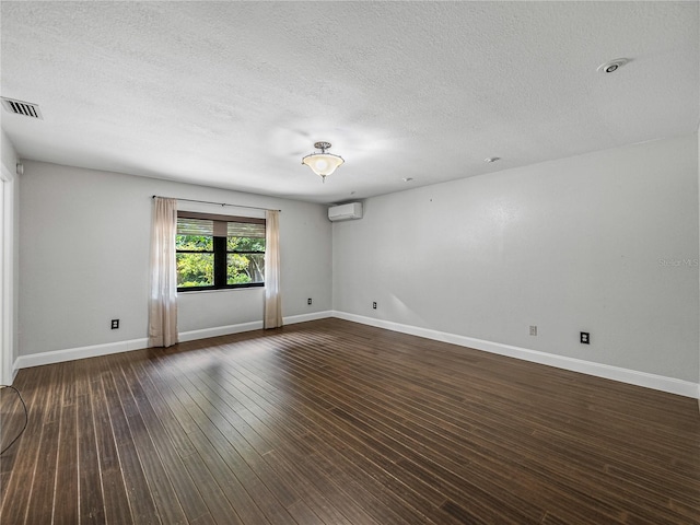 empty room with an AC wall unit, a textured ceiling, and dark hardwood / wood-style flooring