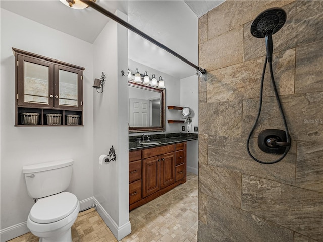 bathroom featuring a tile shower, vanity, and toilet