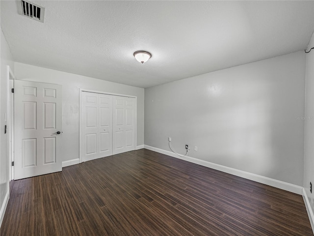 unfurnished bedroom featuring a closet, dark hardwood / wood-style floors, and a textured ceiling