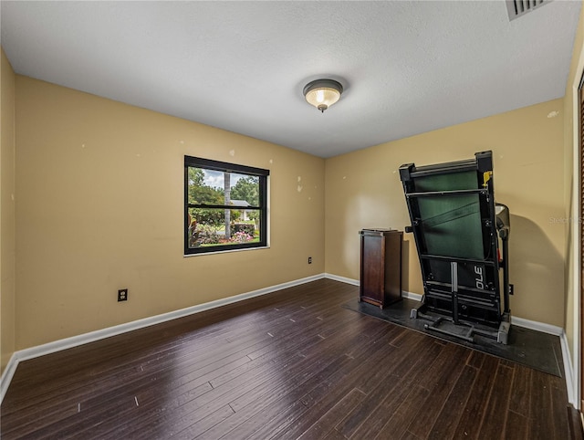 unfurnished living room with a textured ceiling and dark hardwood / wood-style floors