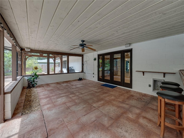 unfurnished sunroom featuring wooden ceiling, a fireplace, ceiling fan, and french doors