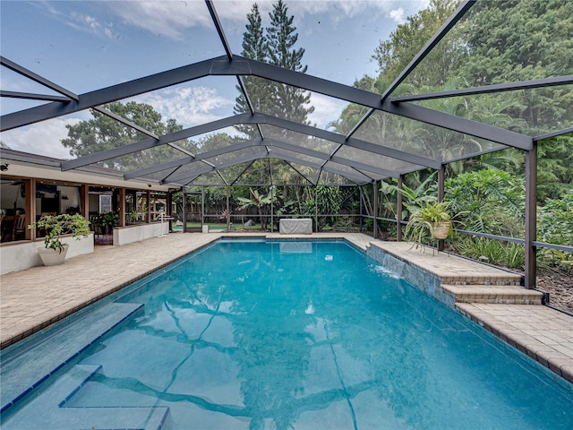 view of swimming pool with glass enclosure, a patio, and pool water feature