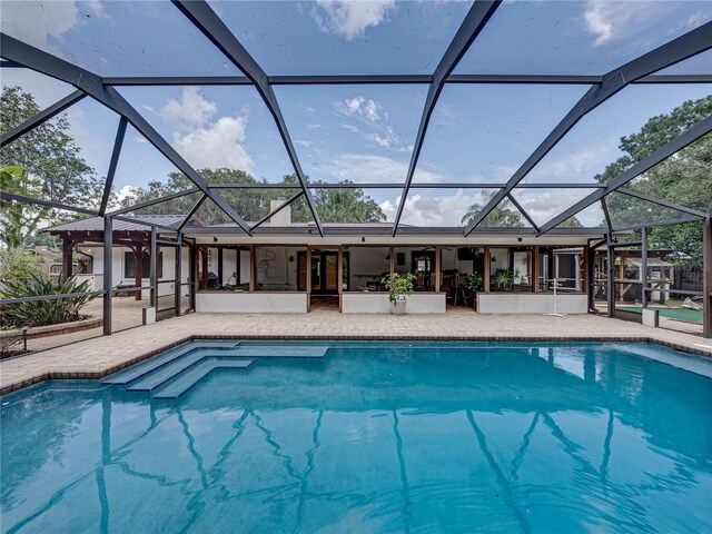 view of pool with glass enclosure and a patio