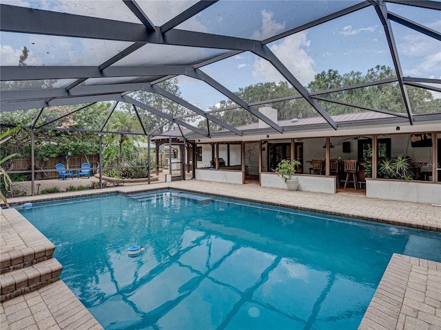 view of pool with glass enclosure and a patio area