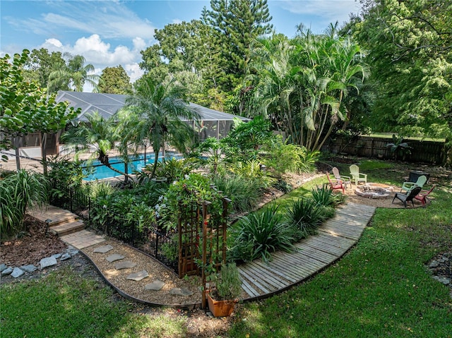 view of yard with a fire pit, a fenced in pool, and glass enclosure