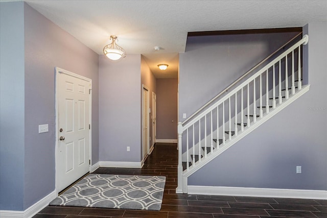 entrance foyer featuring a textured ceiling and dark wood-type flooring